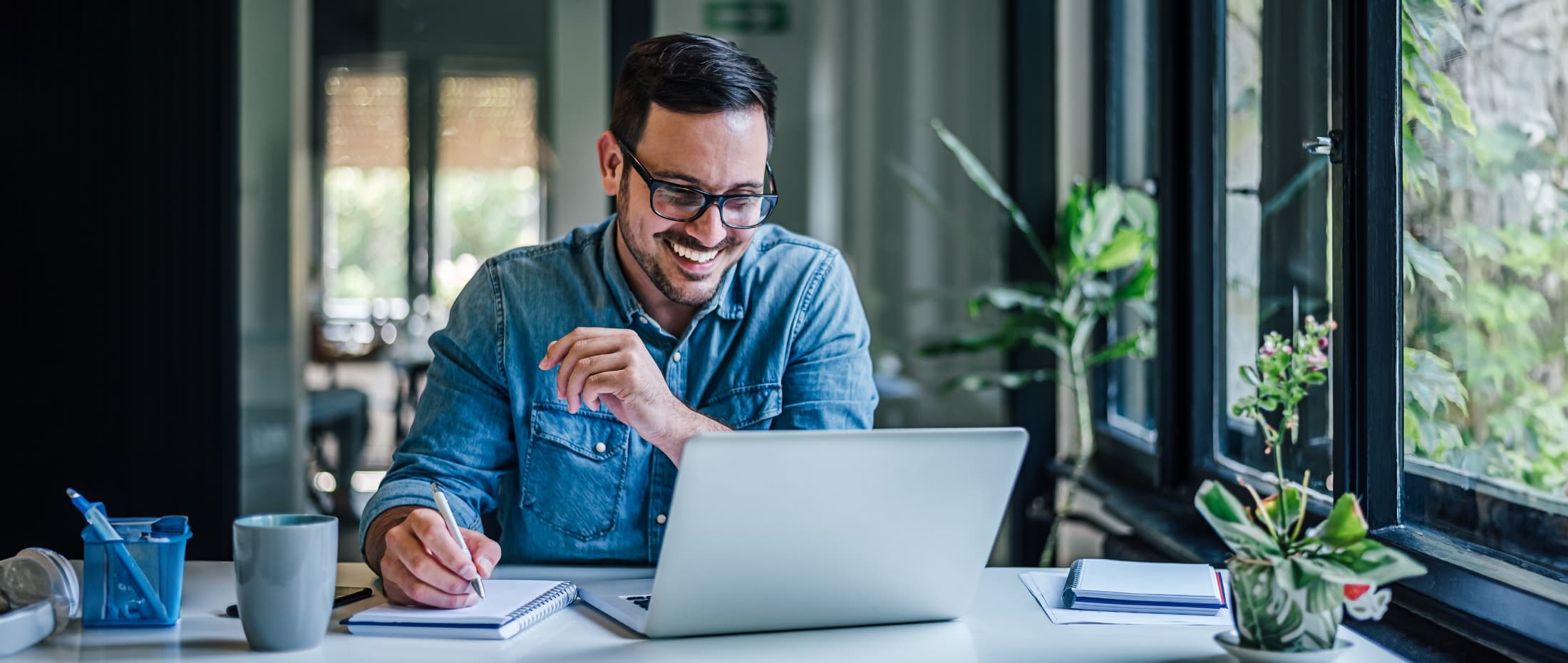 Man looking at his computer and taking notes