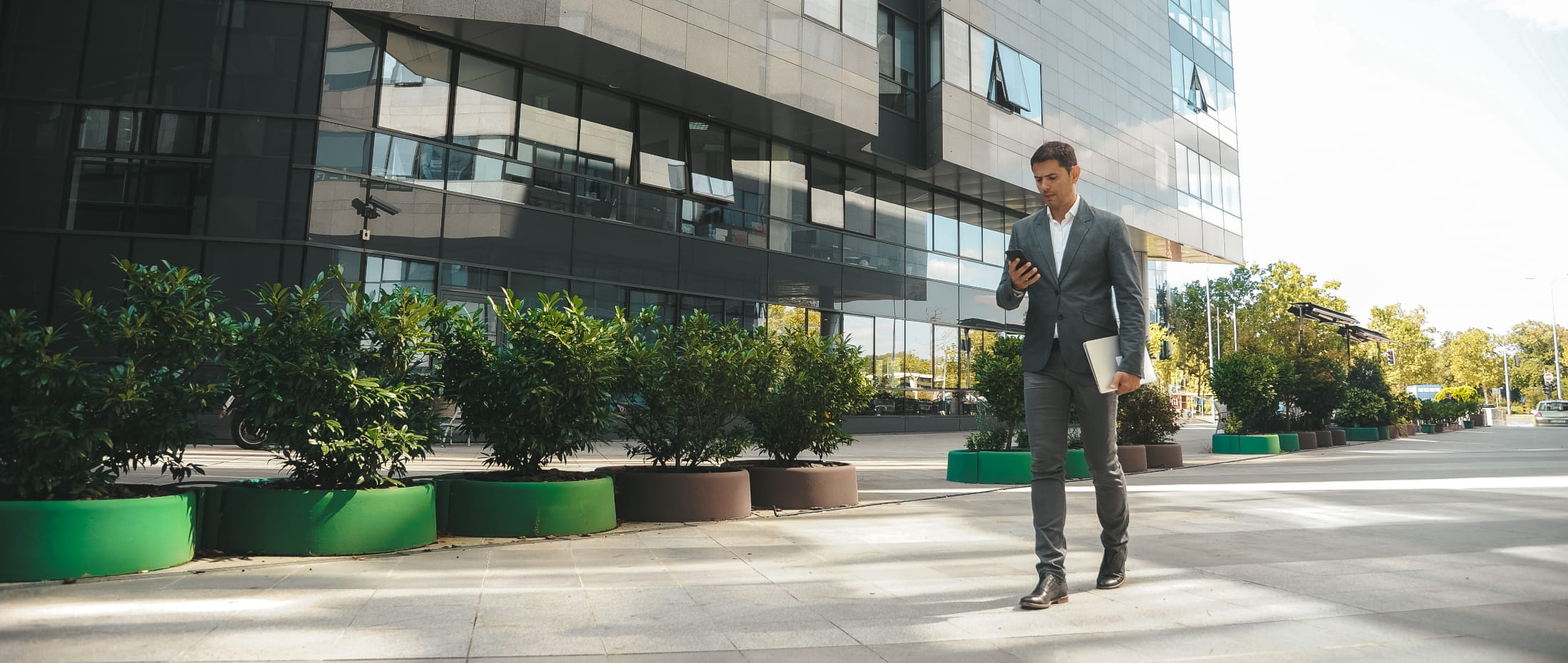 Man looking at his cell phone and walking near an office building